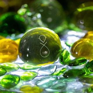 Die grünen Glaskugel im Wasser wirken wir bemooste Kieselsteine in einem kühlen Waldbach.
